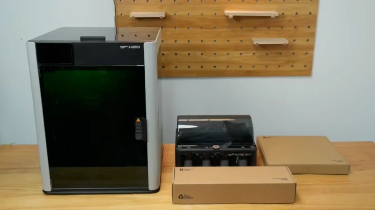 Bambu Lab H2D 3D printer with accessories on a wooden table.